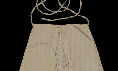A large white fabric pocket (approximately 14" tall by 12" wide at the base), 缝成圆边平顶的三角形的. 上面是长条布料，用来把口袋系在穿着者的腰上.